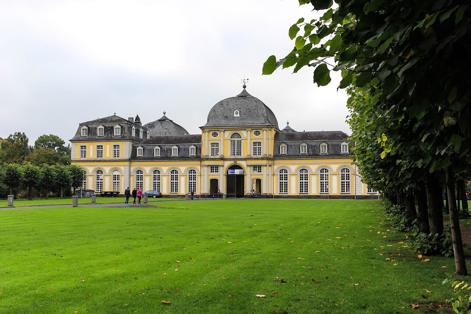 Schloss mit gelber Fassade und großem Rasen